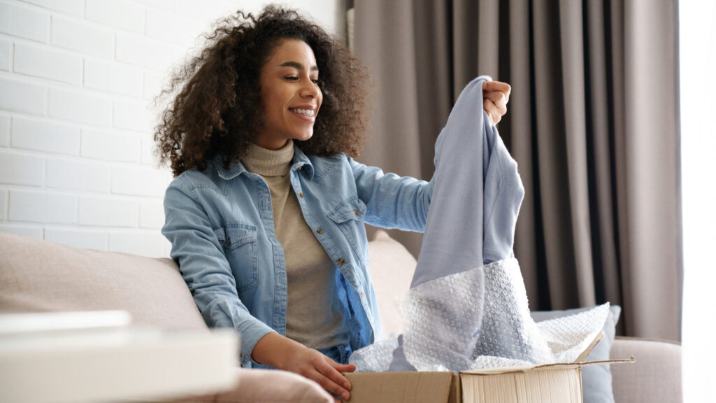 A customer smiles while looking at the clothing she bought from a fundraising webstore.